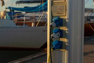 Finlandiya 'da bir yat limanındaki teknelerin şarj istasyonu, Baltık Denizi kıyısında limana demirli iken, yelkenlilerin ve motorlu teknelerin şarj edildiği elektrik prizleriyle dolu.