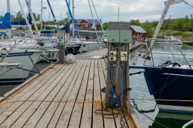 Finlandiya 'da bir yat limanındaki teknelerin şarj istasyonu, Baltık Denizi kıyısında limana demirli iken, yelkenlilerin ve motorlu teknelerin şarj edildiği elektrik prizleriyle dolu.