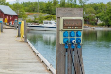 Finlandiya 'da bir yat limanındaki teknelerin şarj istasyonu, Baltık Denizi kıyısında limana demirli iken, yelkenlilerin ve motorlu teknelerin şarj edildiği elektrik prizleriyle dolu.