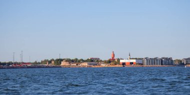 Hanko şehrinin denizden panoramik manzarası, tarihi kırmızı su kulesi, Lüteryen Katedrali, kıyı yaşamı ve mimari yapıları ön plana çıkarıyor.