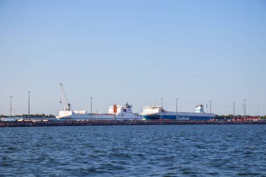 Hanko şehrinin denizden panoramik görüntüsü, yoğun ticari limanı büyük gemilerle gösteriyor, canlı kıyı yaşamını ve deniz faaliyetlerini vurguluyor