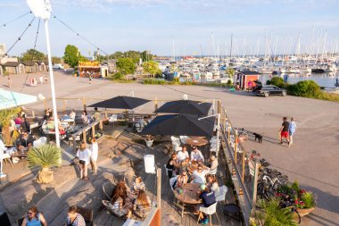 Hanko, Finlandiya - 19 Temmuz 2025: Finlandiya 'nın Hanko kentindeki açık hava barı. İnsanlar rahatlar ve sokak kafelerinde sosyalleşirler. Sıcak havanın ve sahil kasabasının sıcak atmosferinin tadını çıkarırlar.