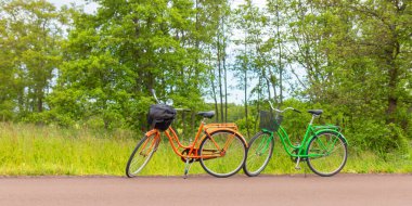 Aland Adaları 'nda sakin bir kırsal yol boyunca park edilmiş iki renkli bisiklet. Sahne, Finlandiya takımadalarında yaz boyunca sürdürülebilir seyahat ve açık hava eğlencesini yansıtır. Pankart