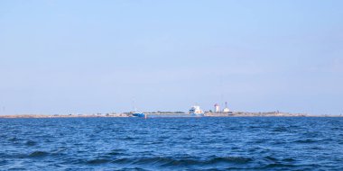 Hanko, Finlandiya - 16 Temmuz 2025: Hanko şehrinin denizden panoramik görüntüsü, yoğun ticari limanı büyük gemilerle gösteriyor, canlı kıyı yaşamı ve deniz faaliyetlerini vurguluyor