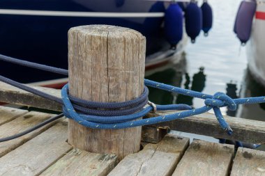 Rıhtıma giden bir tekneyi bağlayan demirleme iplerine yakın plan. Denizcilik, güvenlik, denizcilik ve deniz yolculuğunun ebedi geleneklerini ve denizle bağlantıyı simgeliyor.