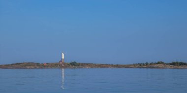 Baltık Denizi 'nde kayalık adada bitişik evi olan küçük bir deniz feneri. Finlandiya 'da geleneksel deniz mimarisi, huzurlu sular ve kuzey ışığı ile kıyı manzarası