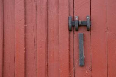Kırmızı boyalı ahşap kapıya yakın metal mandal, sürdürülebilir konut ekolojik İskandinav geleneği ve basit kırsal mimari