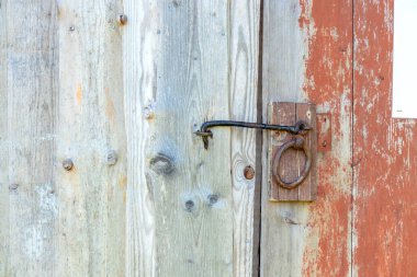 Kırmızı boyalı ahşap kapıya yakın metal mandal, sürdürülebilir konut ekolojik İskandinav geleneği ve basit kırsal mimari