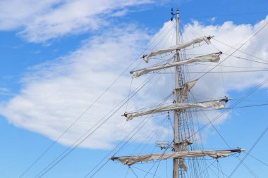 Antika bir yelkenliye sarılı yelkenliler. Geleneksel ahşap gemi, huzurlu deniz atmosferi ve kuzey sahili cazibesiyle sakin liman manzarası.
