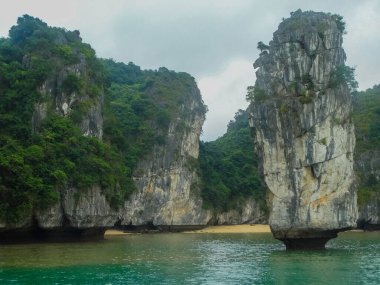 Vietnam, Halong Körfezi 'ndeki su kenarındaki kayalık oluşumların manzarası bölgenin doğal güzelliğini ve jeolojik özelliklerini gözler önüne seriyor..