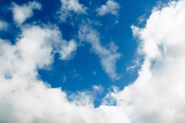 Yumuşak, tüylü beyaz bulutlarla dolu geniş bir gökyüzü manzarası. Görüntü, parlak güneşli bir günün güzelliğini ve dinginliğini doğal bulut oluşumlarıyla yakalar..