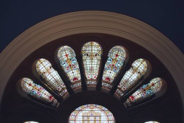 Katedralin içinde koyu arkaplanı olan renkli ve süslü tasarımları olan güzel vitraylı pencereler..