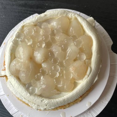 Çok güzel sunulmuş bir tatlı, şeffaf liçi parçaları ve küçük jöleli boncuklarla süslenmiş kremalı beyaz bir kaplama içerir. Bu tatlı şey her durum için mükemmeldir..