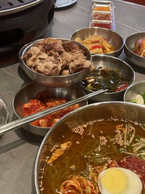 Izgara et, renkli mezeler ve bir kase baharatlı şehriye içeren lezzetli bir Kore barbeküsü masanın üzerine seriliyor. Lokantalar bu aşçılık deneyimini tatmaya hazır..