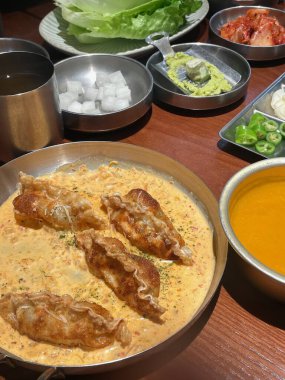 Kore 'de canlı bir yemek deneyimi kremalı sosun içine yerleştirilmiş çıtır çıtır hamur köfteleri sergiliyor, yanında da marul, kimçi ve sos da dahil olmak üzere çeşitli mezeler..