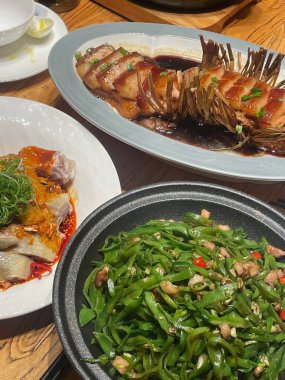 Çok güzel düzenlenmiş bir masa, baharatlı yeşil fasulye tabakları ve baharatlı etle süslenmiş bir balığın yanı sıra tüm bir balığa ev sahipliği yapar. Yüzlerce lokantacı canlı atmosferin tadını çıkarıyor..