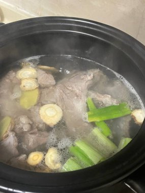 Yumuşak et parçaları bir tencerede zencefil, sarımsak ve yeşil soğanla kaynayarak lezzetli bir et suyu oluşturuyor. Buhar yükselir, hazırlık için sıcak ve davetkar bir yemeği gösterir..