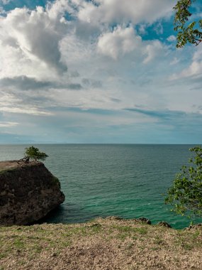 Aceh 'teki Lamreh Sahili' nin çarpıcı manzarasında el değmemiş beyaz kum, yemyeşil ağaçlar ve kasvetli, dramatik bir gökyüzüne karşı engebeli kayalar var. Seyahat, doğa ve plaj temalı içerik için mükemmel