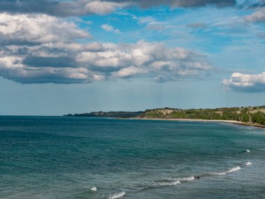 Aceh Besar 'daki Lamreh Denizi' nin çarpıcı manzarası berrak ve yumuşak beyaz kumları, berrak okyanus suyunun yanında sergiliyor, yeşil tepeler görkemli bir şekilde yükseliyor, gökyüzü güzel bulutlarla süslenmiş.