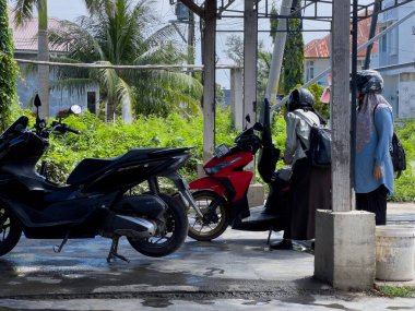 Aceh, Endonezya - 26 Eylül 2024: Ahşap bir yer olan Acehnese toplumuna ait geleneksel bir koğuşta motosiklet yıkayan bir işçi