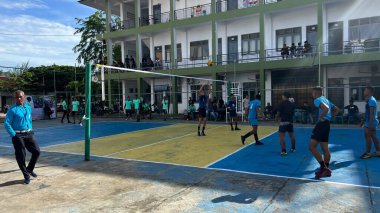 Aceh, Endonezya - 14 Haziran 2023: Bir grup voleybol oyuncusu sarı ve mavi voleybol sahasında, seyirciler maçı izliyor.