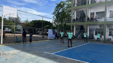 Aceh, Endonezya - 14 Haziran 2023: Bir grup voleybol oyuncusu sarı ve mavi voleybol sahasında, seyirciler maçı izliyor.