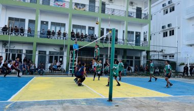 Aceh, Endonezya - 14 Haziran 2023: Bir grup voleybol oyuncusu sarı ve mavi voleybol sahasında, seyirciler maçı izliyor.