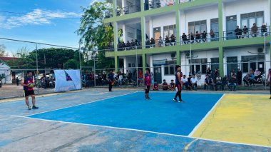 Aceh, Endonezya - 14 Haziran 2023: Bir grup voleybol oyuncusu sarı ve mavi voleybol sahasında, seyirciler maçı izliyor.