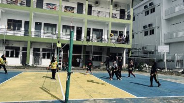 Aceh, Endonezya - 14 Haziran 2023: Bir grup voleybol oyuncusu sarı ve mavi voleybol sahasında, seyirciler maçı izliyor.