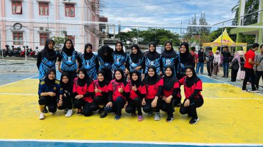 Aceh, Endonezya - 14 Haziran 2023: Bir grup voleybol oyuncusu sarı ve mavi voleybol sahasında, seyirciler maçı izliyor.
