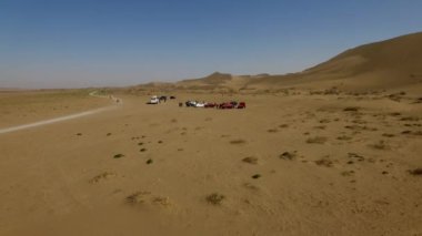 İnsanlar çölde kum tepelerinde eğleniyor. Off-road sürüşü. Develer. tırmanıyor.