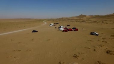 İnsanlar çölde kum tepelerinde eğleniyor. Off-road sürüşü. Develer. tırmanıyor.