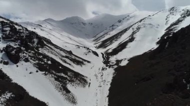 Kocaman karlı dağ ve kar. Karlı dağların arasında İHA ile uçmak.