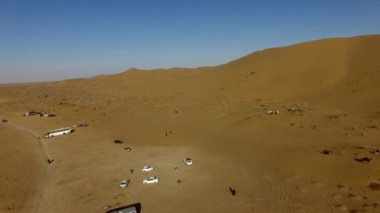 İnsanlar çölde kum tepelerinde eğleniyor. Off-road sürüşü. Develer. tırmanıyor.