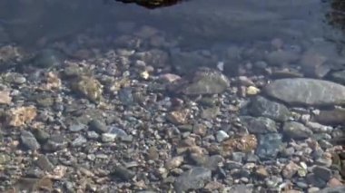 Çekim temiz bir su akışını yakalar, altındaki taşları ortaya çıkarır ve küçük dalgalar yaratır..