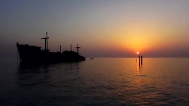 Gün batımında denizde bir geminin silueti.