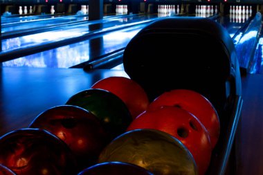 Sanatsal bowling fotoğrafı, duvar kağıdı. Loş atmosferik ışıklandırmalı bowling şeridi. Bowling topları yeni yapılmış boş bir sokakta rafta duruyor.
