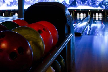 Sanatsal bowling fotoğrafı, duvar kağıdı. Loş atmosferik ışıklandırmalı bowling şeridi. Bowling topları yeni yapılmış boş bir sokakta rafta duruyor.