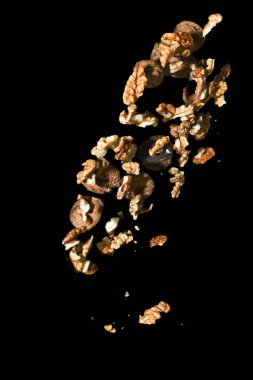 Birçok ceviz, siyah arka planda izole bir şekilde havaya atıldı. Dar odaklı. Kırılmamış fındık ve kırılmış fındık karışımı..