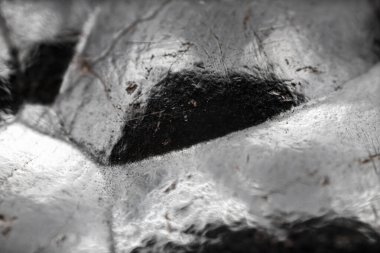 Çiğ hematite yakın çekim. Demir cevheri yüzeyi, gri yansıtıcı mineral dokusu.