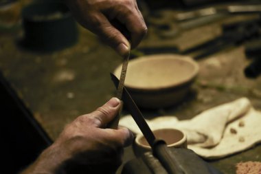 Erkekçe kollar keskinleştiriyor ve çekiç kullanarak eski bir bıçağı onarıyor.