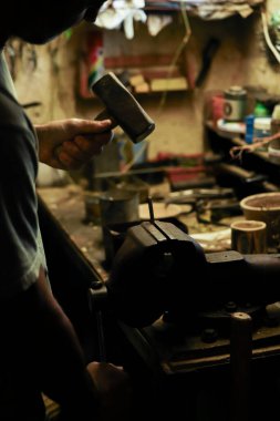 Erkekçe kollar keskinleştiriyor ve çekiç kullanarak eski bir bıçağı onarıyor.