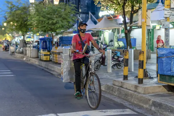 Gece vakti Endonezya 'nın bir caddesinde Bisikletli Adam Malzemeleri Teslim Ediyor