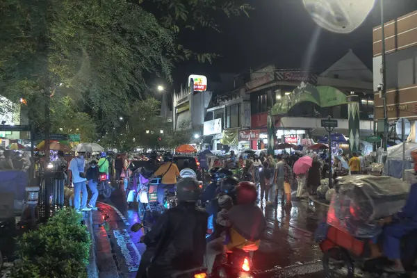 Endonezya 'da yoğun bir caddenin gece manzarası. Motosikletler ve yağmurda insanlarla dolu.