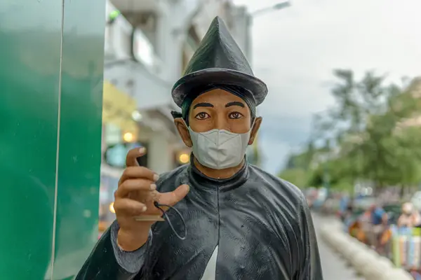 Sokak sahnesinde maske takan birinin heykeli.