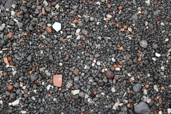 Siyah çakıl ve kaya parçalarıyla kaplı bir yüzeye yakın çekim