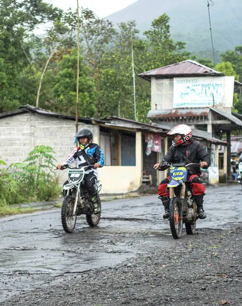 Dağlık bir bölgede engebeli bir yolda motosiklet süren motosikletliler.