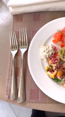 Enginar, tavuk salatası ve somon balığı beyaz tabakta eko-bilinçli bileşenleri vurguluyor. Bu sofistike otel yemeği, sürdürülebilir hoşgörü ve gurme lezzetlerini birleştirir..