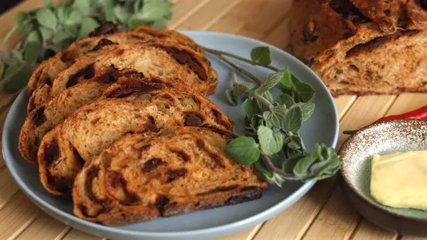 stock image Mediterranean-style vegan plate featuring sliced bread with tomato and olives baked into loaf served alongside vegan butter hint of chili fresh greens Eco-conscious dish that is nutritious satisfying