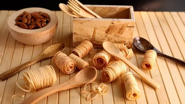 stock image Wooden bowl of almonds paired with wooden spoons and cutlery. Natural setup underscores sustainability and eco-conscious choices for those seeking healthy, plant-based eating options Natural wood